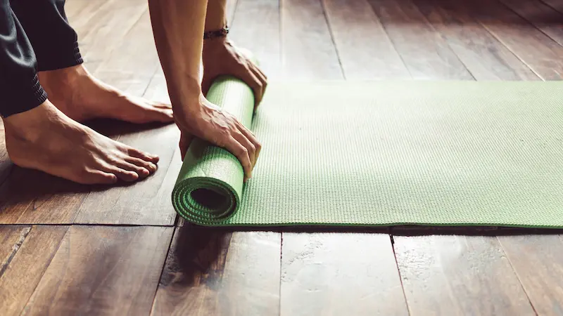 close up of a man hand rolling a green yoga mat